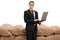 Businessman with a laptop in front of a pile of burlap sacks