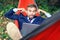 Businessman with laptop relaxs in a hammock on nature. He talking on video chat and doing funny faces with his tongue hanging out