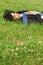 Businessman lies on back on grass with closed eyes