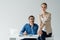 businessman in love sitting at workplace and looking at his colleague while she sitting on his desk