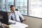 Businessman Making Phone Call Sitting At Desk In Office