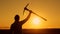 Businessman man in hard hat stands background sunset with pickaxe raised up, back view. Cryptocurrency man stands