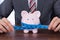 Businessman measuring piggybank with measure tape