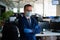 Businessman in medical mask and gloves works in an open space office. Male middle manager in a suit follows safety