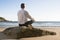 Businessman meditating on a beach