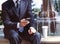 Businessman with a mobile phone and coffee near the fountain