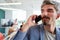 Businessman with mustache and goatee talking on smart phone in conference room at workplace