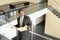 Businessman With Newspaper Leaning On Glass Railing