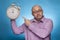 A businessman in a piked shirt pointing with the index finger on a huge alarm clock
