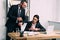 businessman pointing at watch near concentrated businesswoman at workplace with laptop