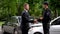 Businessman and policeman shaking hands car accident scene, collision settlement
