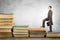 Businessman with portfolio goes up stairs of books