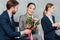 Businessman presenting flowers to beautiful smiling asian businesswoman