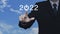 Businessman pressing 2022 start up business icon over blue sky with white clouds, Business happy new year 2022 cover concept