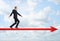 Businessman in profile walking straight ahead the big red arrow on the background of the blue sky.