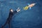 A businessman pulling up his hands to a flying through the sky rocket painted on a blackboard