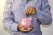 A businessman put a coin in a pink piggy bank and saved the money to plan ideas.