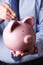 Businessman Putting Coin Into Large Piggy Bank