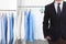 Businessman and rack with clean clothes at dry-cleaner`s. Space for text