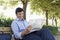 Businessman Reading Newspaper On Bench