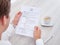 Businessman reading resume with tea cup on desk