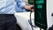 Businessman recharge his electric car from charging station. Peruse
