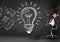 Businessman relaxing on chair against light bulb on blackboard