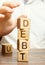 Businessman removes wooden blocks with the word Debt. Reduction or restructuring of debt. Bankruptcy announcement. Refusal to pay