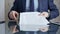 Businessman reviewing documents at office desk. Close-up of a professional man's hands examining paperwork with pen