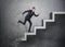 Businessman running up concrete staircase, which is crushing down after him