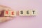 businessman`s hand holding wooden cubes block to complete reset word, for restart, reopen or renew business, change or