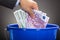 Businessman`s Hand Throwing Euro Notes In Blue Bucket