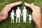 Businessman`s Hands Covering Paper Family On Grass