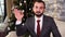 Businessman saying hello, waving hand to greet you in cozy room with christmas holidays decorations