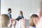 Businessman shaking hands with colleague while audience clapping at conference