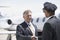 Businessman Shaking Hands With Pilot And Aircraft In Background