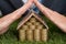 Businessman shielding house of coins and euro note on grass