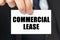 Businessman shows a card with the text - COMMERCIAL LEASE