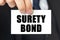 Businessman shows a card with the text SURETY BOND