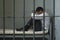 Businessman Sitting On Bed Behind Bars