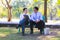 Businessman,They are sitting on bench in park.He is play notebook and  search internet.A