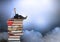 Businessman sitting on Books stacked by atmospheric clouds