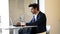 Businessman sitting in cafe, drinking fresh coffee typing with his laptop.