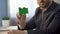 Businessman sitting at desk in office, showing green colored card, bank services