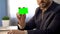 Businessman sitting at desk in office, showing green colored card, bank services