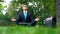 Businessman sitting on grass in forest and meditating after hardworking day