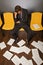 Businessman sitting with head in hands, documents scattered on floor