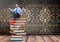 Businessman sitting meditating on Books stacked by decorative wallpaper antique