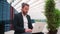 Businessman sitting outside with laptop working remote distant job outdoors near office