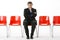 Businessman Sitting In Row Of Empty Chairs